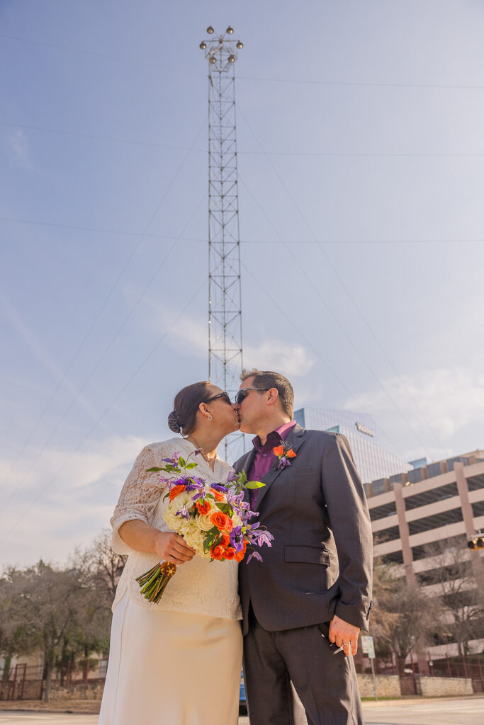 Rachele and Wes share a kiss in the bright afternoon sun with one of Austin's moon towers in the background.