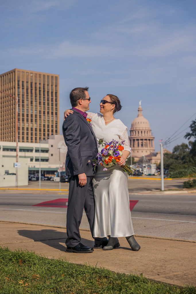 Rachele throws her arm around Wes' shoulder as they pose in front of the pink granite dome of the Texas State Capitol.