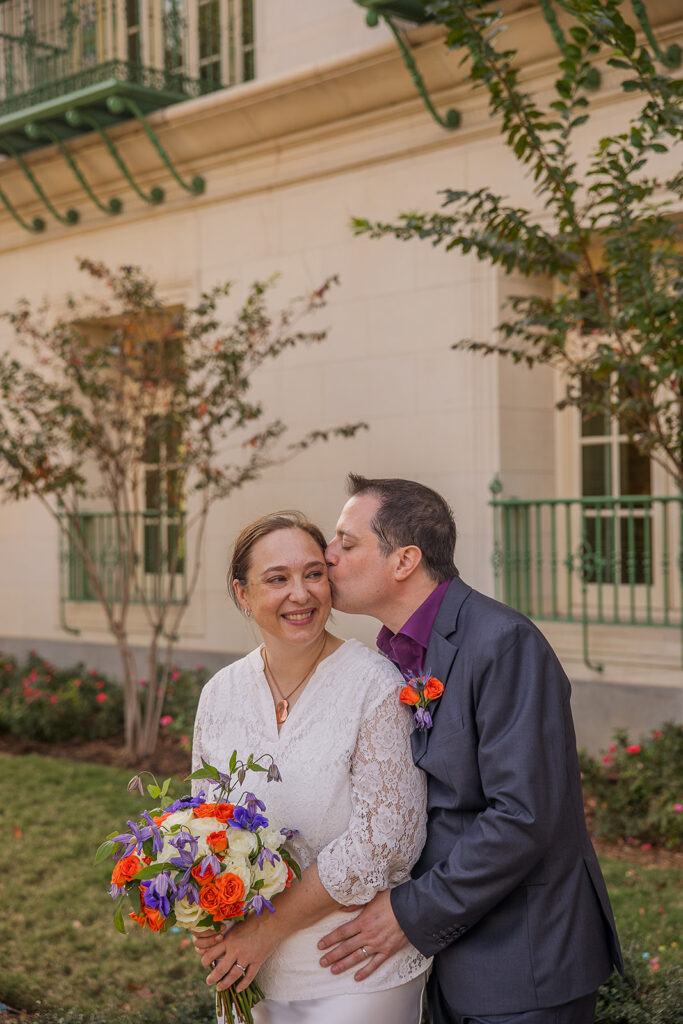 Wes kisses the side of Rachele's head tenderly with his eyes closed as she smiles and glances back.