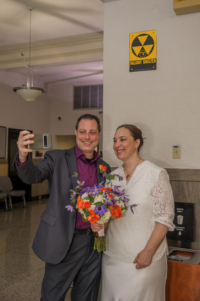 Wes and Rachele taking a selfie with a Fallout Shelter sign on the wall behind them.